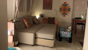 Una sala acogedora con un sofá, una mesita y un papel tapiz estampado.