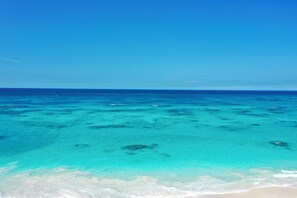 A clear view of a beach with turquoise water and white sand.