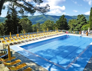 A swimming pool with yellow lounge chairs and a view of mountains. - Holiday Resort in Villanova D'albenga (Villanova d'Albenga)