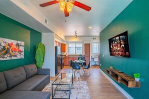 A modern living room with a sofa, a glass coffee table, and a dining area with chairs and a table. - Walk To Westgate w/ Modern Pool, Gym, Parking, W/D (Glendale)