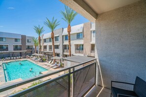 A hotel pool area with multiple levels of balconies, palm trees, and lounge chairs. - Walk To Westgate w/ Modern Pool, Gym, Parking, W/D (Glendale)