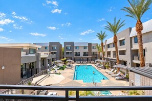 A hotel with a central swimming pool surrounded by lounge chairs and palm trees. - Walk To Westgate w/ Modern Pool, Gym, Parking, W/D (Glendale)