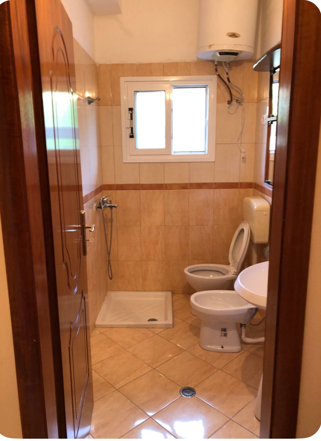 A small bathroom with a shower, toilet, and sink.