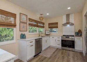 Una cocina moderna con armarios blancos, estufa de acero inoxidable y lavavajillas.