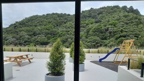 A rooftop patio with a picnic table, potted plants, and a children's play area with a slide.