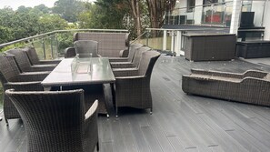 A deck with wicker furniture, including a table and chairs, and a glass railing.