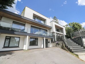 A modern two-story building with a covered outdoor area and a staircase leading to a balcony.