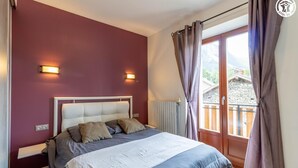 A bedroom with a bed, two wall-mounted lights, a window with curtains, and a view of a balcony. - LE BÛCHER - VAL CENIS (VAL CENIS)
