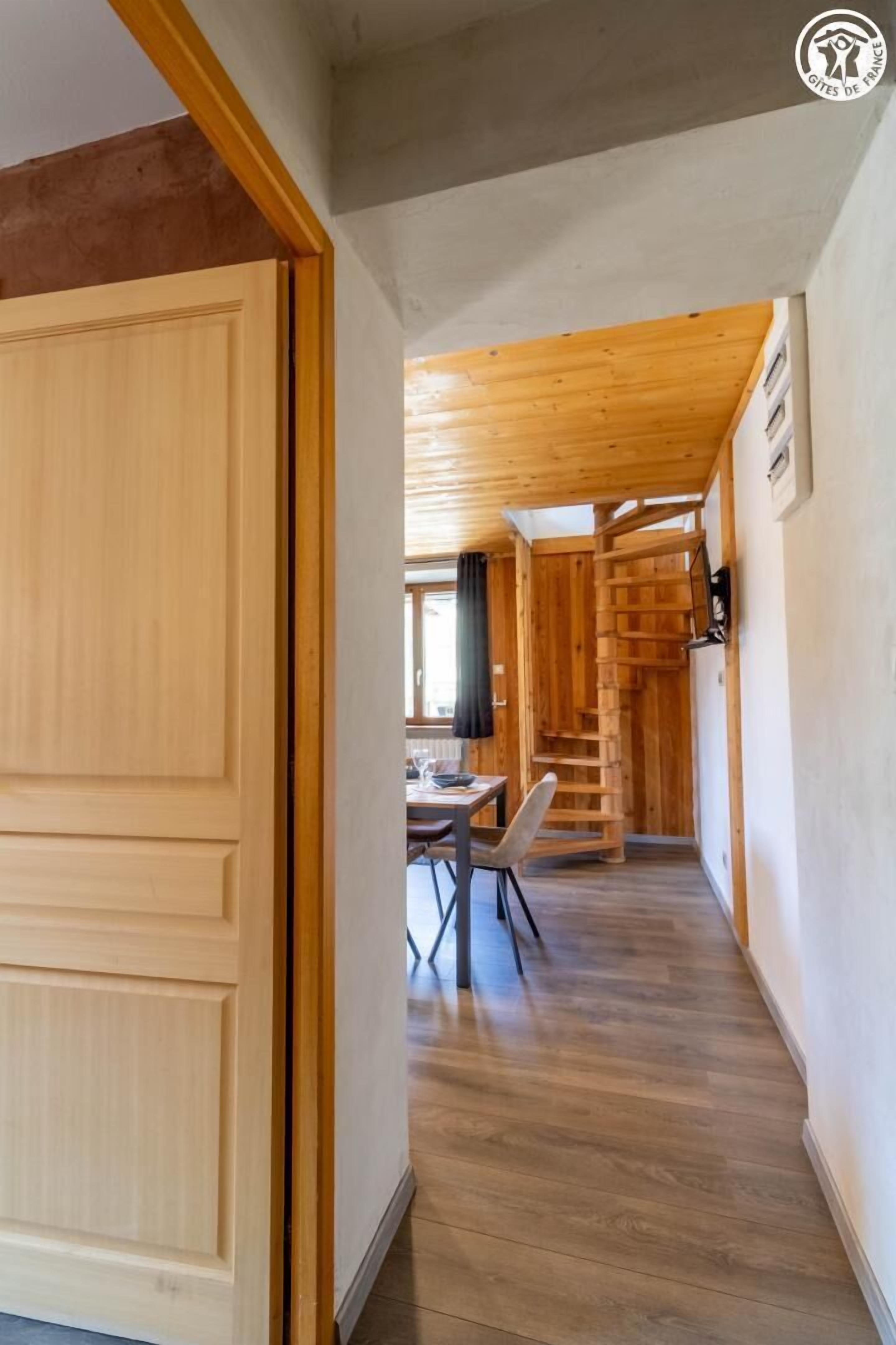 A wooden interior with a staircase leading to a dining area.