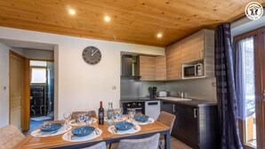 A modern kitchen with wooden cabinets, a microwave, and a clock on the wall. - LE BÛCHER - VAL CENIS (VAL CENIS)