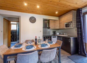 A modern kitchen with wooden cabinets, a microwave, and a clock on the wall.