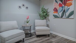 A room with two armchairs, a small table with a potted plant, and a large floral painting on the wall. - Charming Spacious Home with Game room (Columbus)