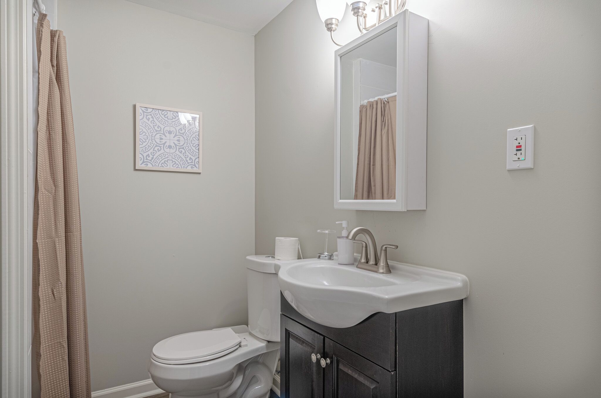 A bathroom with a toilet, sink, and mirror.