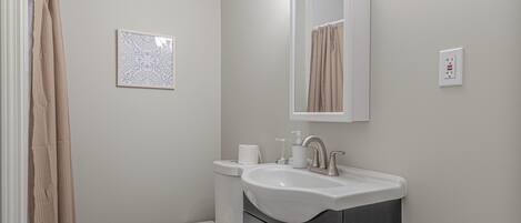 A bathroom with a toilet, sink, and mirror.