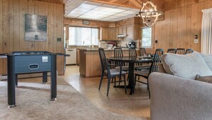 A cozy wooden cabin interior with a dining area, kitchen, and a foosball table. - Amazing 3-bedroom Home in Beautiful Blue Lake Springs, Arnold California (Arnold)