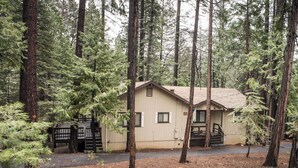 A cabin with a simple design, surrounded by tall trees, and accessible by a small driveway. - Amazing 3-bedroom Home in Beautiful Blue Lake Springs, Arnold California (Arnold)