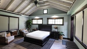 Une chambre à coucher avec un grand lit, une table de chevet, une commode et une plante en pot.