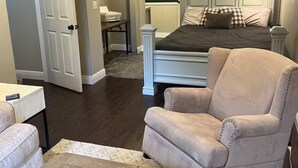 A bedroom with a bed, a chair, a desk, and a TV mounted on the wall.