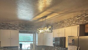 A modern kitchen with white cabinets, stainless steel appliances, and a large window providing natural light.
