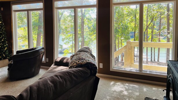 A living room with a large window, a leather sofa, and a Christmas tree.