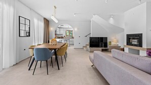 A modern living room with a sofa, TV, and dining area with chairs and a table. - Oasis of peace Villa Bianca (Vodnjan)