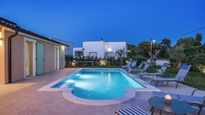A rectangular swimming pool with a small hot tub, surrounded by lounge chairs and a table with a candle. - Oasis of peace Villa Bianca (Vodnjan)