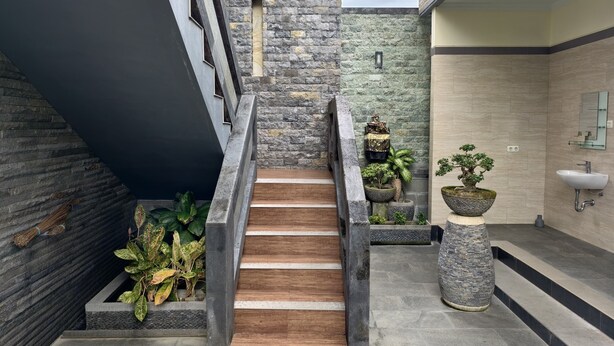 A modern staircase with stone walls and wooden steps, leading to a bathroom with a sink and a mirror. - Ayuna Guest House – Comfortable & Affordable in Bali (Bali)