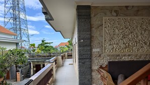 A corridor with a stone wall and a carved floral panel, leading to a staircase. - Ayuna Guest House – Comfortable & Affordable in Bali (Bali)