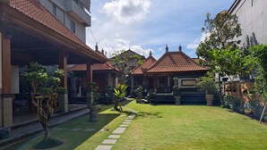 A courtyard with a paved walkway, traditional tiled roofs, and potted plants. - Ayuna Guest House – Comfortable & Affordable in Bali (Bali)