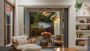 An open-plan living area with a wooden dining table, cushioned seating, and a view of the backyard. - Group-Friendly 4BR | Steps from East Austin Fun (Austin)