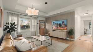 A modern living room with a leather sofa, a coffee table, a TV, and a cityscape view. - NEW! Charcoal & Charm!! (Spring Hill)