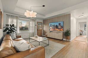A modern living room with a leather sofa, a coffee table, a TV, and a cityscape view.