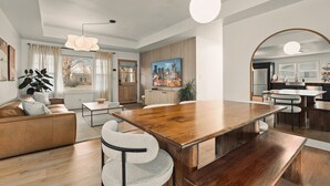 A modern living room with a wooden dining table, a sofa, and a large window with curtains. - NEW! Charcoal & Charm!! (Spring Hill)