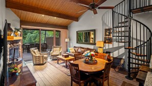 A spacious living area with a wooden ceiling, a dining table, and a spiral staircase.