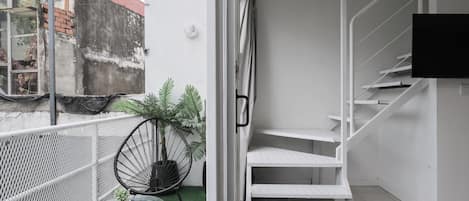 A modern apartment with a balcony, a white staircase, and a TV mounted on the wall.