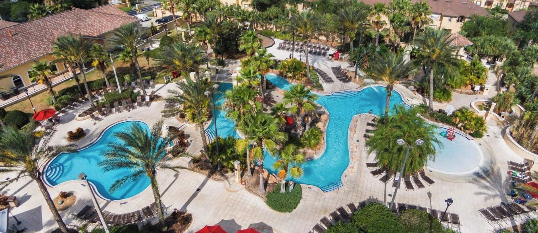 Un resort con varias piscinas, palmeras y zonas de descanso.
