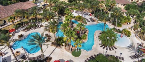 Un resort con varias piscinas, palmeras y zonas de descanso.