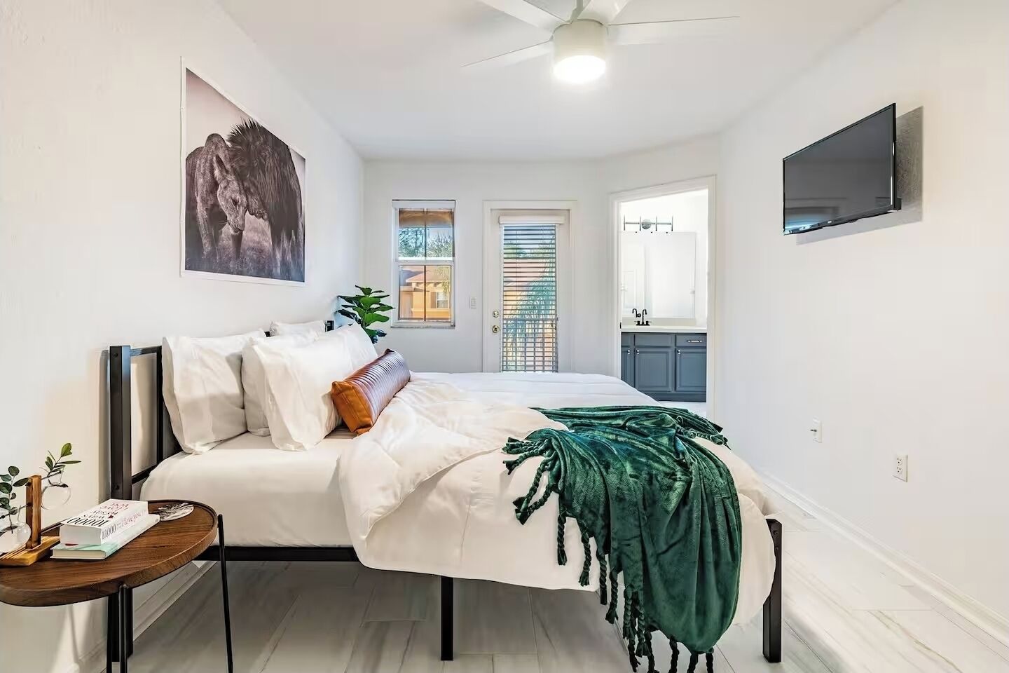 A bedroom with a bed, bedside table, and a TV mounted on the wall.