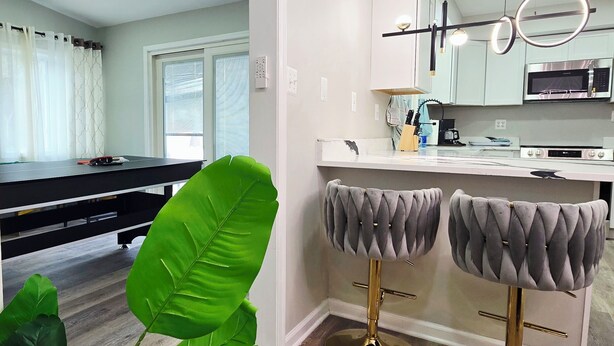 A modern kitchen with white cabinets, a stainless steel microwave, and a bar area with two stools. - Spacious & beautiful 4-bedroom in a peaceful Severn, close to DC & Baltimore (Severn)