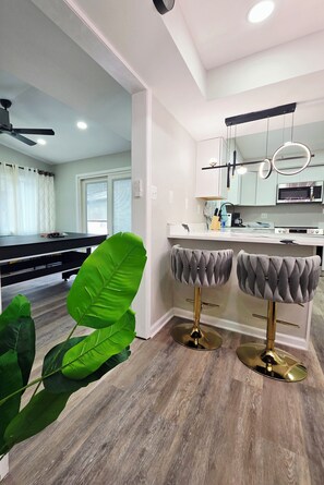 A modern kitchen with white cabinets, a stainless steel microwave, and a bar area with two stools. - Spacious & beautiful 4-bedroom in a peaceful Severn, close to DC & Baltimore (Severn)