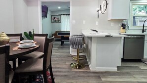 A modern kitchen with a central island, a dining area with a dark wood table and chairs, and a patterned rug. - Spacious & beautiful 4-bedroom in a peaceful Severn, close to DC & Baltimore (Severn)