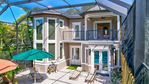 Ein zweistöckiges Haus mit überdachter Terrasse, Pool und Balkon.