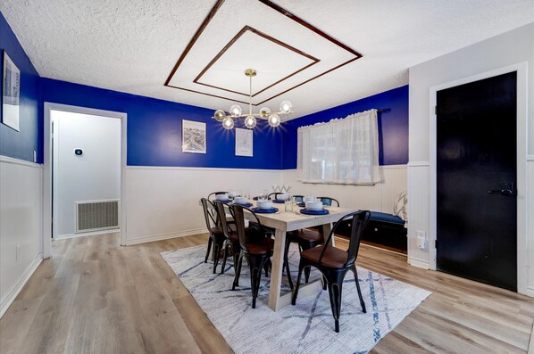 Een eetkamer met een houten tafel gedekt voor zes personen, omringd door zwarte stoelen.