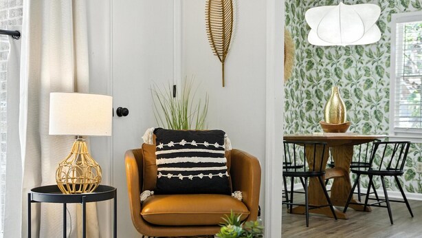 A living room with a brown leather sofa, a round coffee table, a side table with a lamp, and a dining area with a wooden table and chairs. - Cozy Cottage Home in Mount Pleasant (Mount Pleasant)