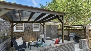 A patio with a covered seating area, brick walls, and a grill. - Cozy Cottage Home in Mount Pleasant (Mount Pleasant)