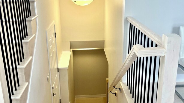 A staircase with white railings, a light fixture above, and a small landing area with a counter. - Entire basement with large windows, private full bathroom and office (Ottawa)