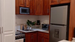 Una cocina con armarios de madera, un refrigerador de acero inoxidable, un microondas y una estufa.