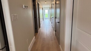 A long, narrow hallway with wooden flooring and white walls. - Duplexes on Hawthorne (Dauphin)