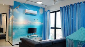 A room with a large window, a flat-screen TV, and a mural of the ocean.