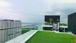 A modern building with a glass balcony overlooking a body of water and a cityscape.